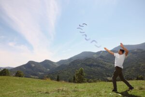 Man throwing boomerang in mountains on sunny day.